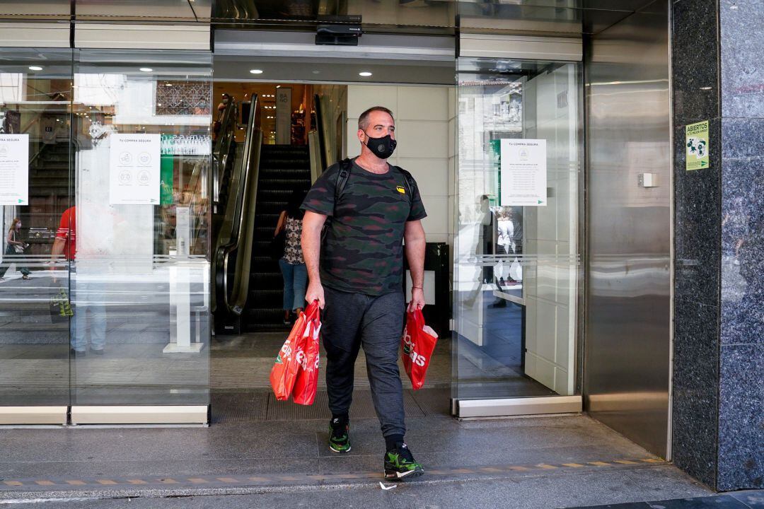 Un hombre sale con varias bolsas de un establecimiento de la capital en plenas rebajas de verano, a 25 de junio de 2021