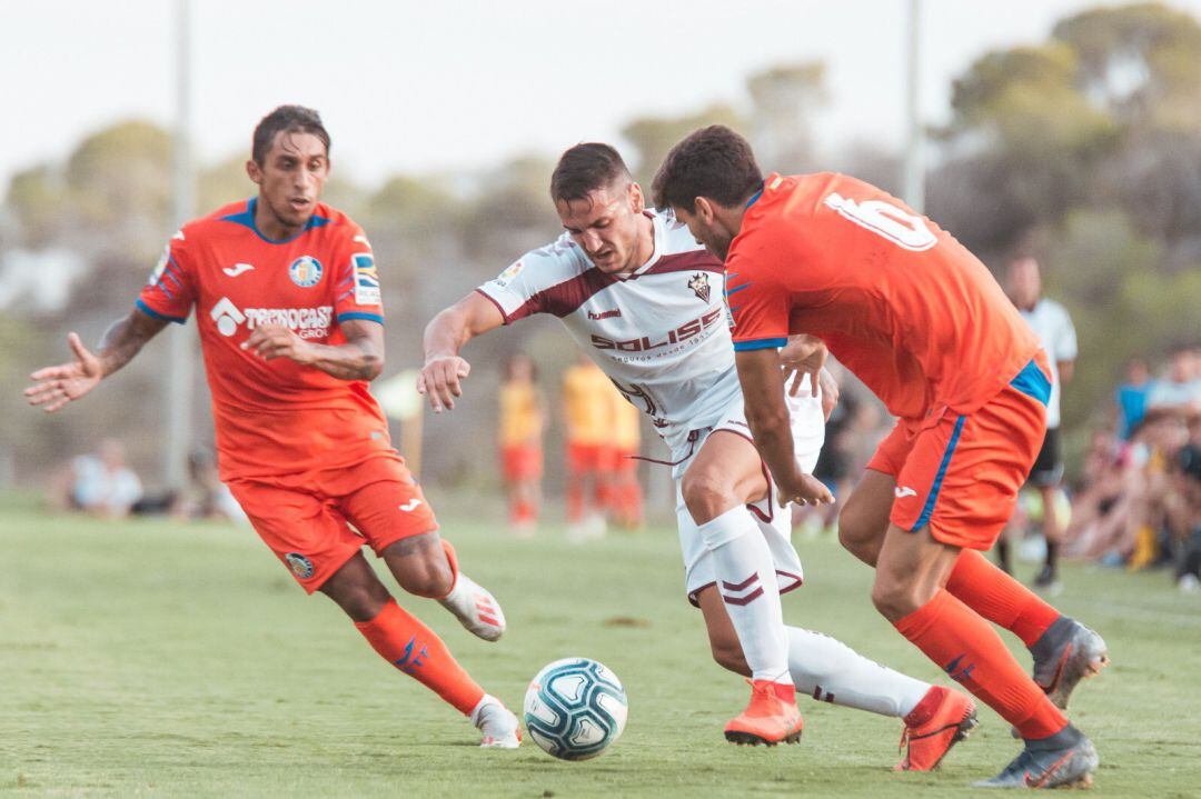 Cabrera (d) y Damián (i) y intentan arrebatar el balón a un jugador albaceteño en el amistoso disputado en Campoamor.