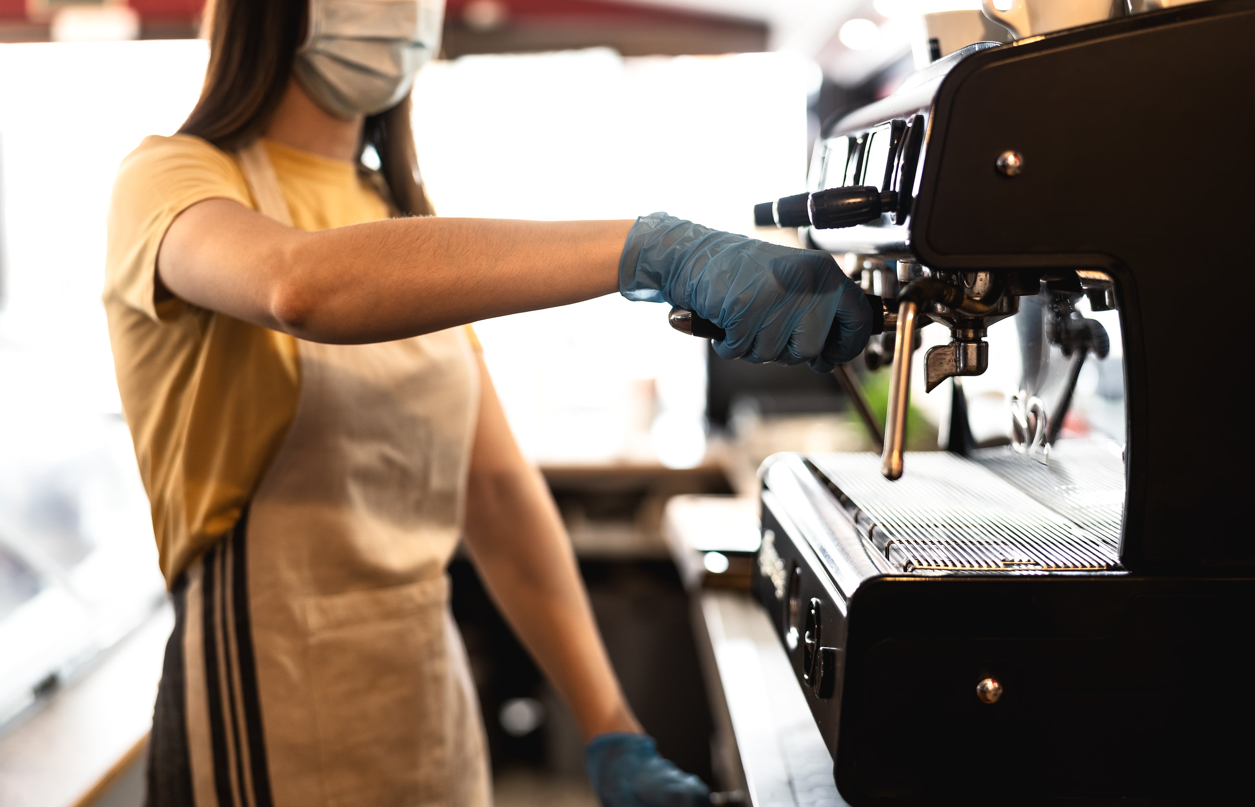 Una mujer jóven sirve café en un establecimiento de hostelería