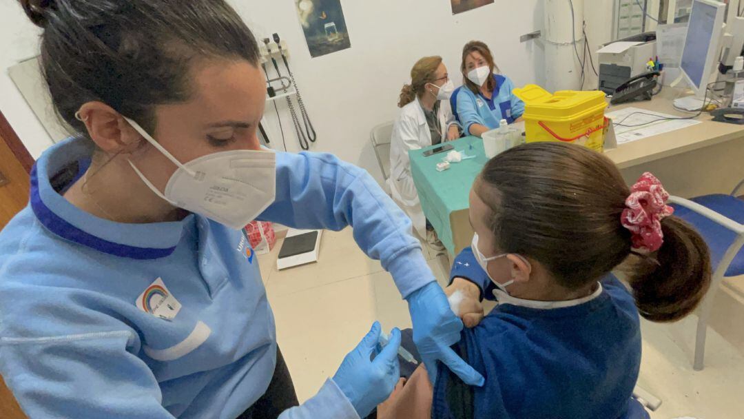 Una profesional sanitaria vacuna a una niña contra la Covid19.