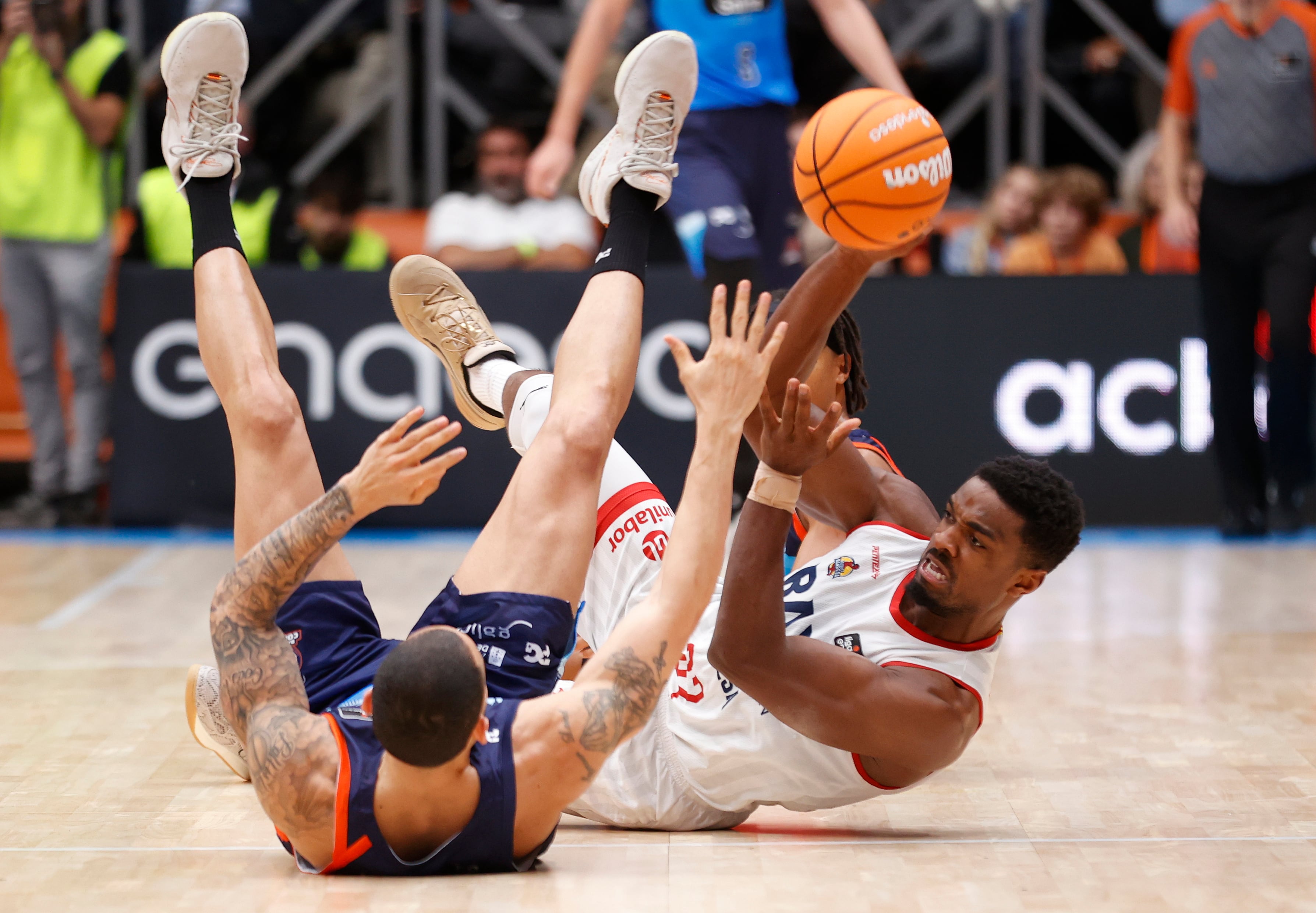 Yunio Barrueta y Derrick Alston Jr. disputan un balón en el suelo