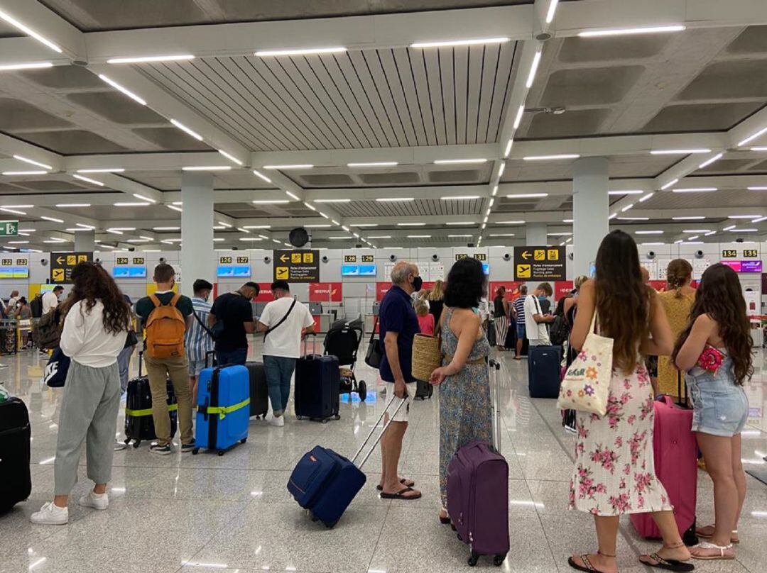 Turistas con mascarilla hacen cola en la zona de facturación del Aeropuerto de Palma
