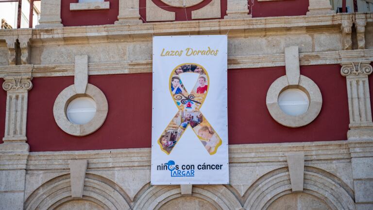 La campaña 'Enciende la esperanza' sobre el cáncer infantil cuelga su lazo dorado en el Teatro Apolo de Almería.