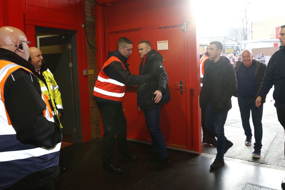 Wayne Rooney es cacheado por un trabajador de Old Trafford. 