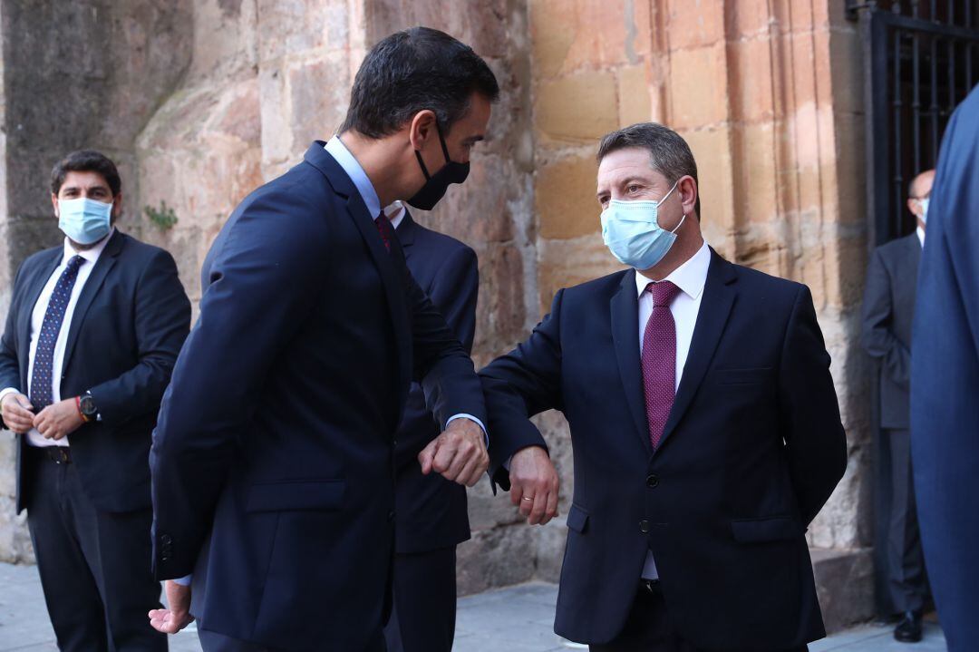 El presidente del Gobierno, Pedro Sánchez, saluda con el codo al presidente de Castilla-La Mancha, Emiliano García-Page (d), a su llegada al Monasterio de Yuso 