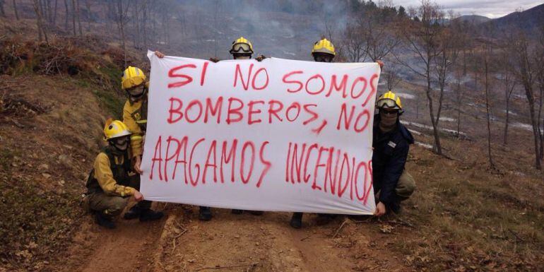 Varios bomberos portan una pancarta