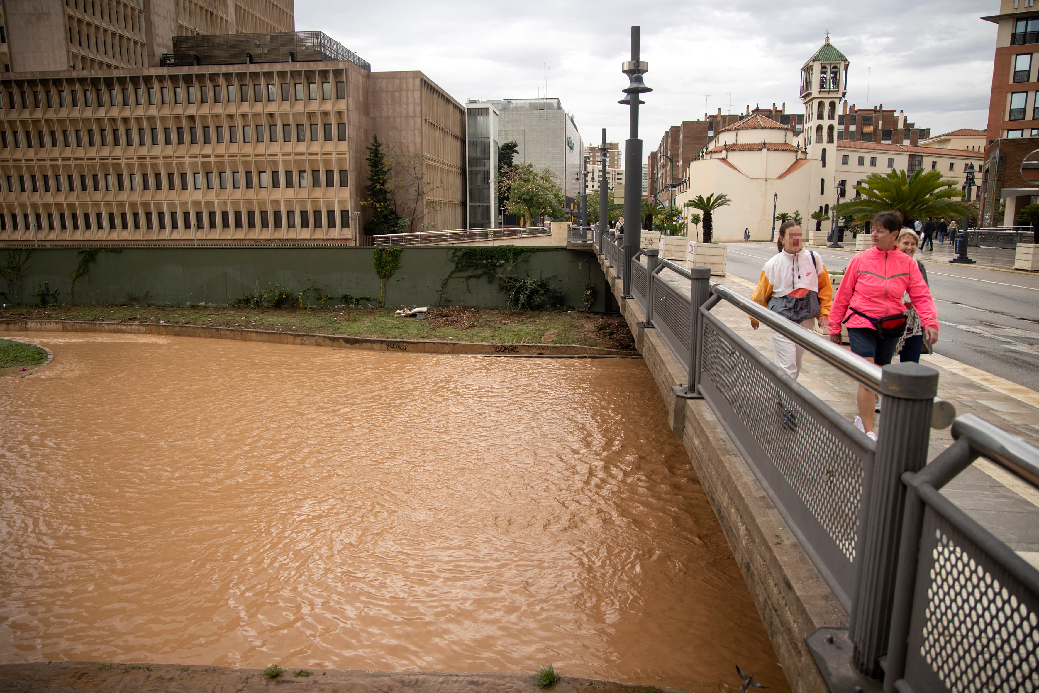 Varias personas caminan y observan el río Guadalmedina a su paso por Málaga capital durante el pasado 29 de octubre, después de las fuertes lluvias caídas en las últimas horas debido al paso de la dana.EFE/Daniel Pérez