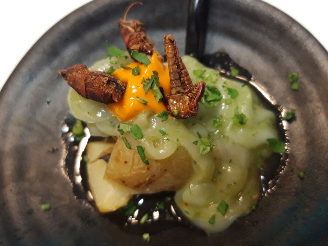 Chapulines con papas asadas, sepia y yema de huevo de corral.