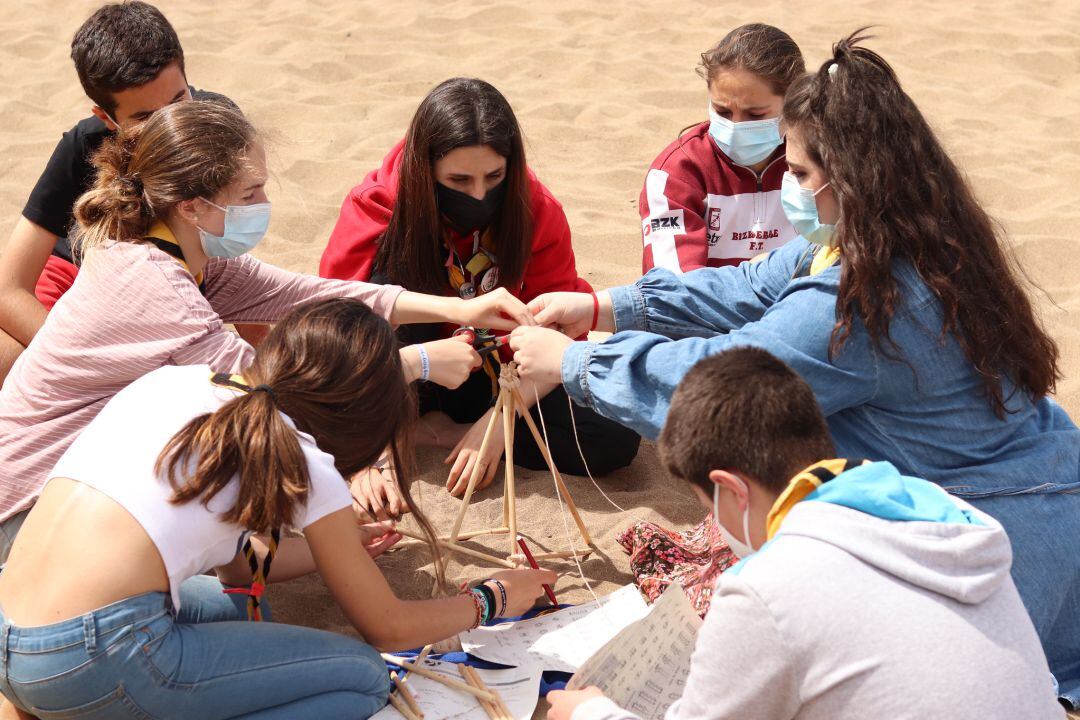 Un grupo de adolescentes realiza actividades manuales en la playa.