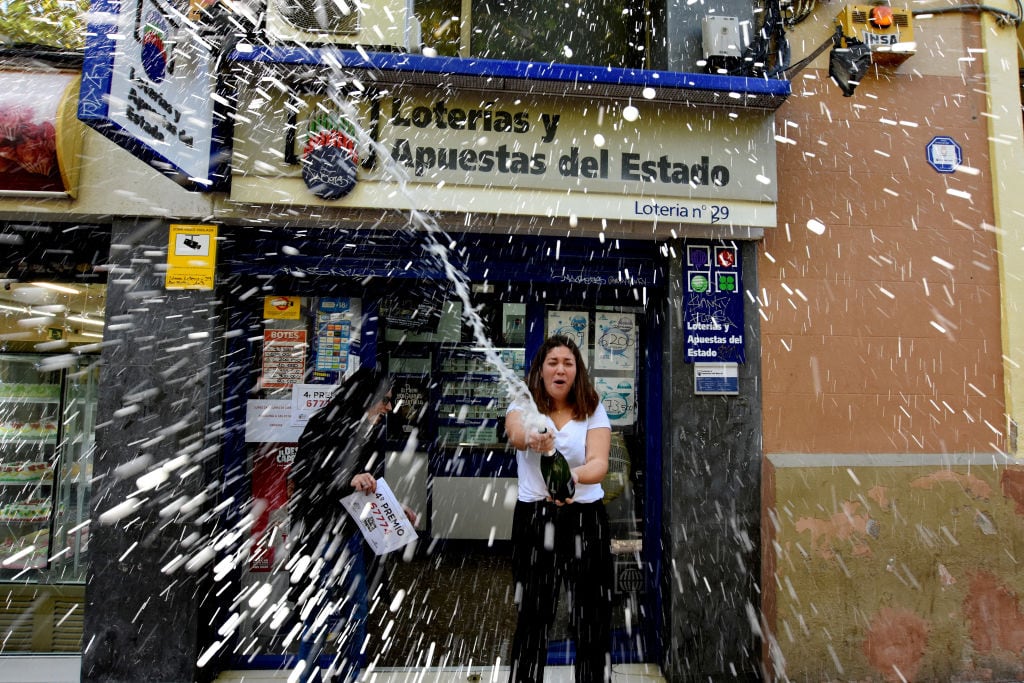 Una mujer celebra con champán en una administración un premio de lotería.