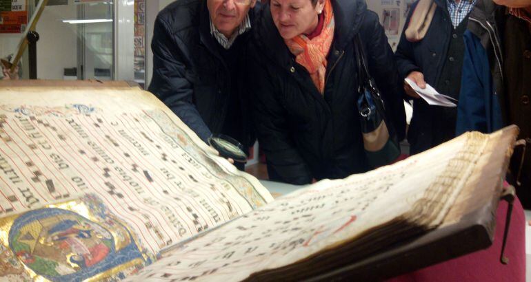 Un grup de visitants analitza els dibuixos en miniatura al peu d&#039;aquest cantoral antic, profusament il.lustrat.