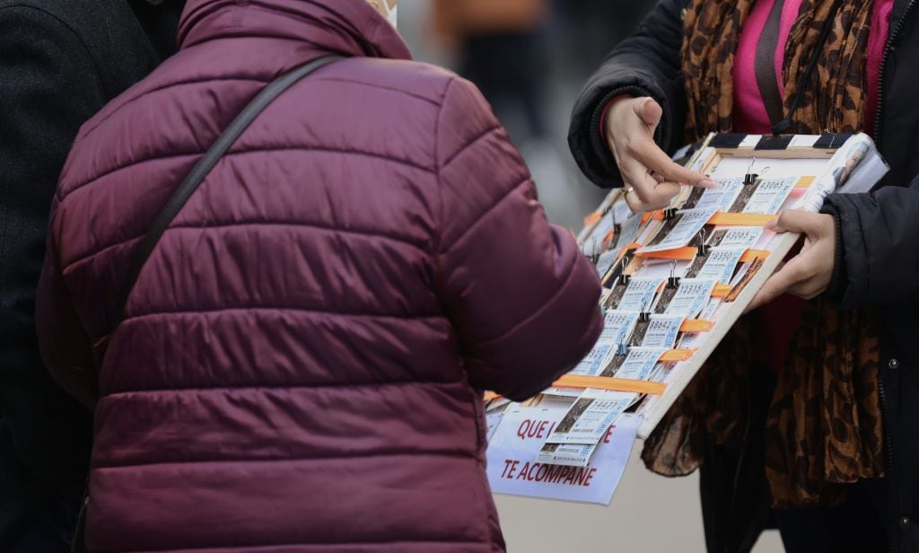 Una lotera enseña a sus clientes décimos de la Lotería de Navidad.