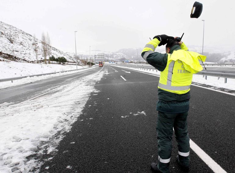 GRA404. ARENAS DE IGUÑA (CANTABRIA), 04/02/2015.- Un Guardia Civil de tráfico pierde su gorra a causa del fuerte viento en la A-67, que une Cantabria con la Meseta, que permanece cortada a consecuencia de la nieve caida en las últimas horas. EFE/Esteban C