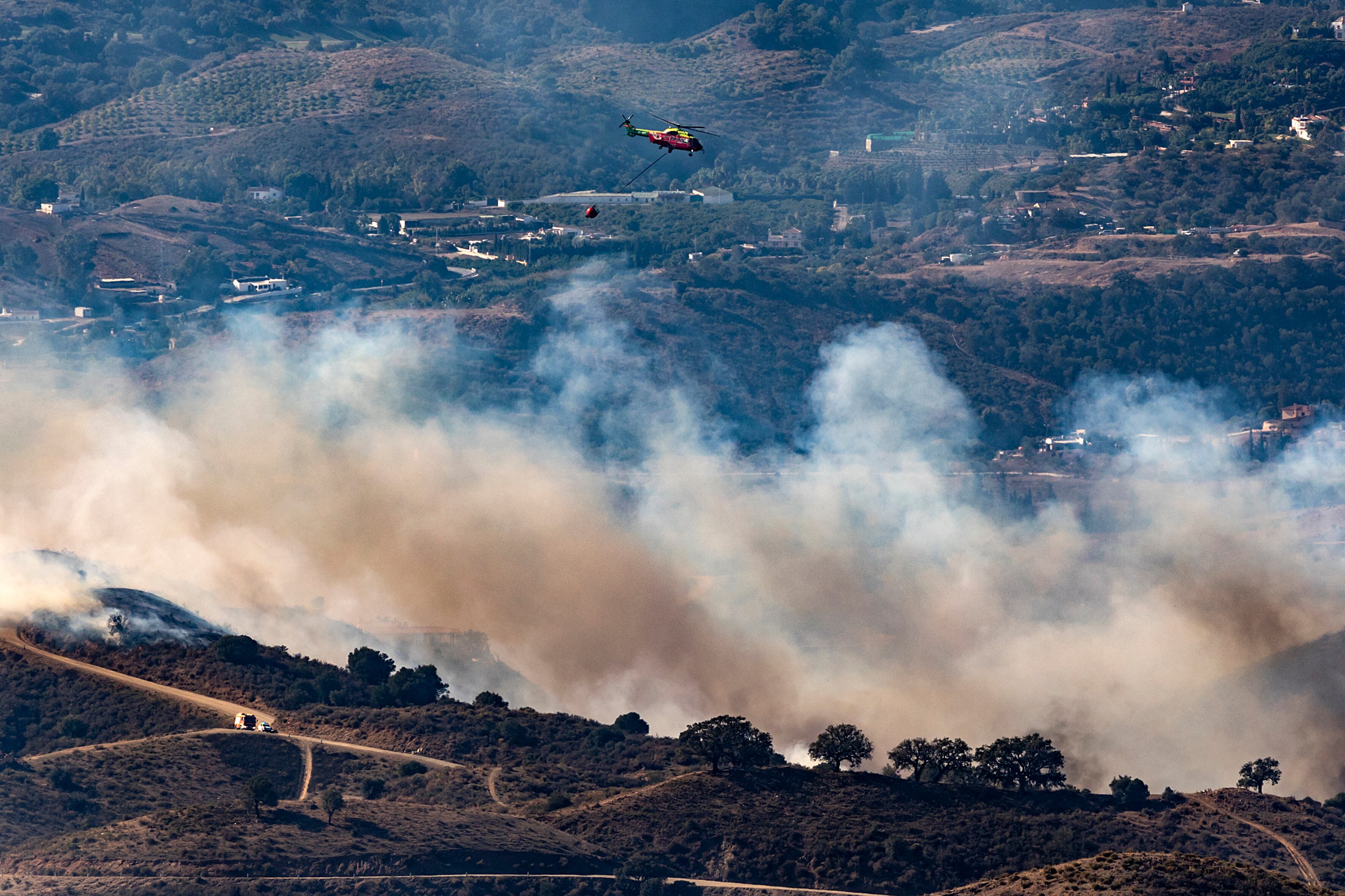 Medios terrestres y aéreos trabajan en la extinción de un incendio forestal en la zona de Valtocado de Mijas (Málaga). EFE/Daniel Pérez