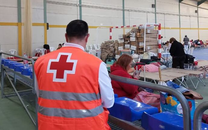 Un voluntario de Cruz Roja atiende a las personas que pasaron la noche en el polideportivo de Linares-Baeza