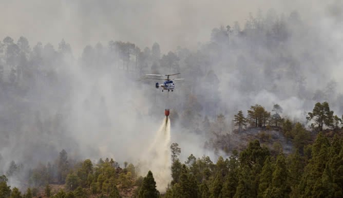 Un helicóptero vierte agua en un bosque afectado por las llamas en Vilaflor