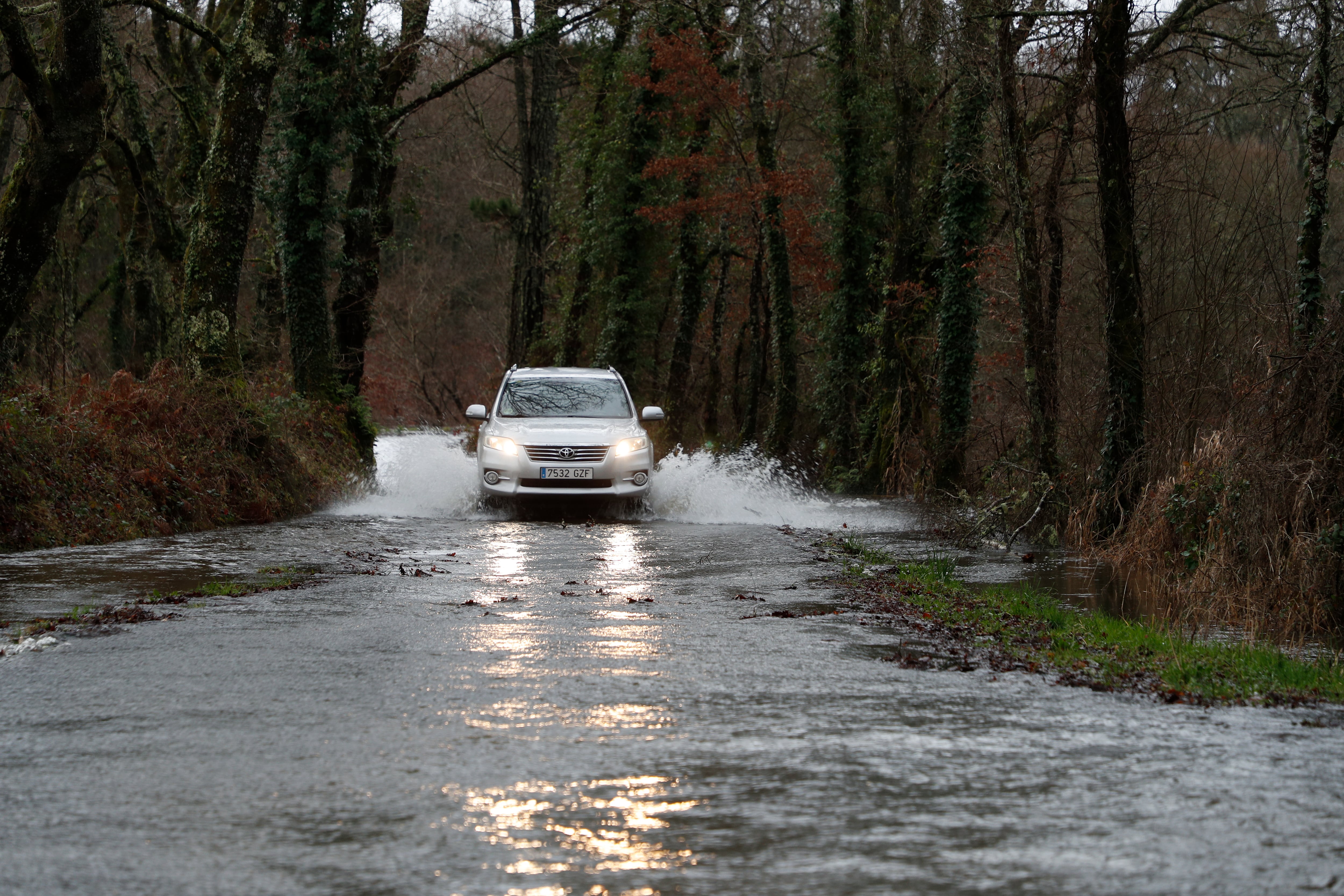 Un coche circula por una carretera anegada por el río Ladra en Insua (Vilalba), provincia de Lugo.