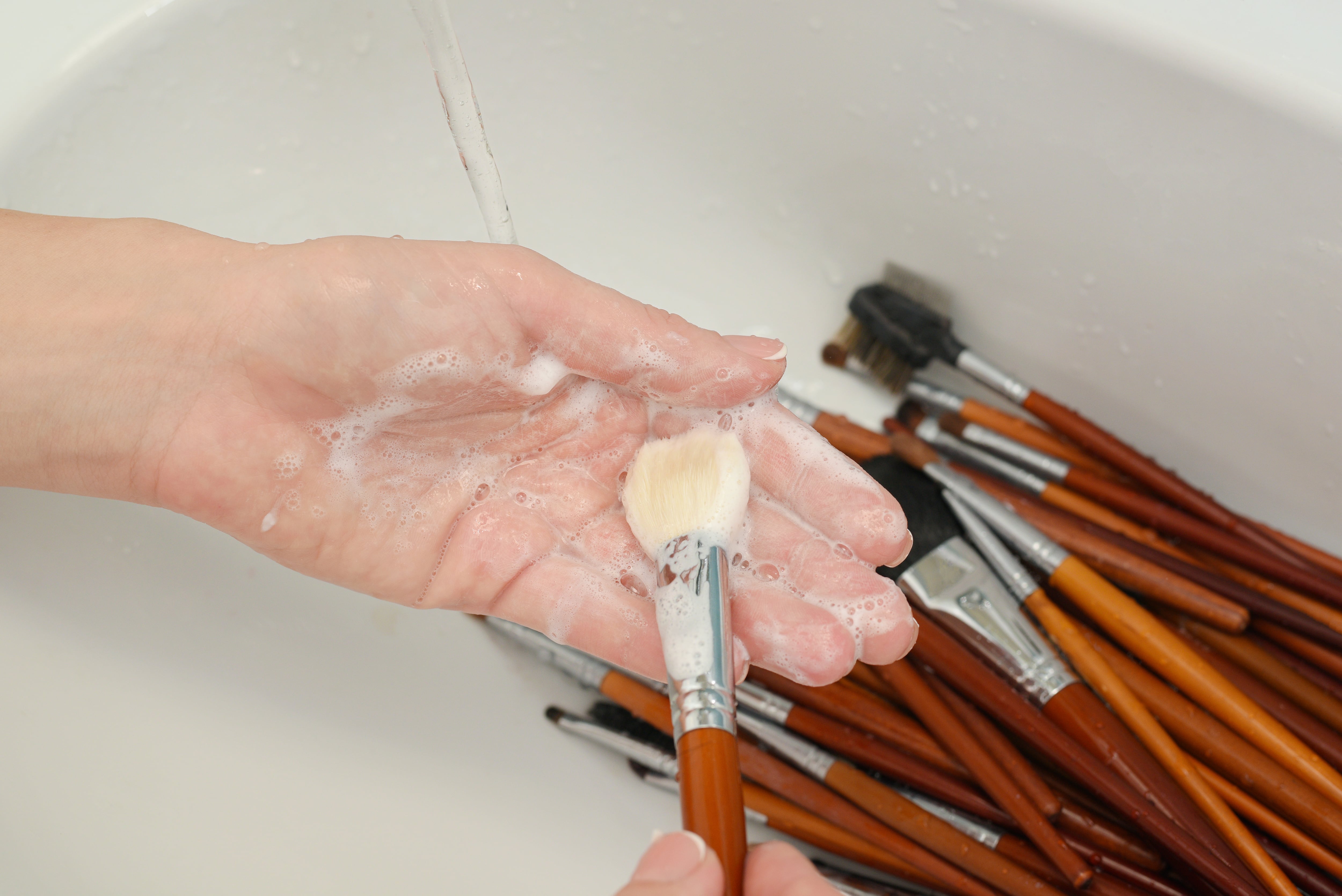 Una persona lava sus brochas de maquillaje.