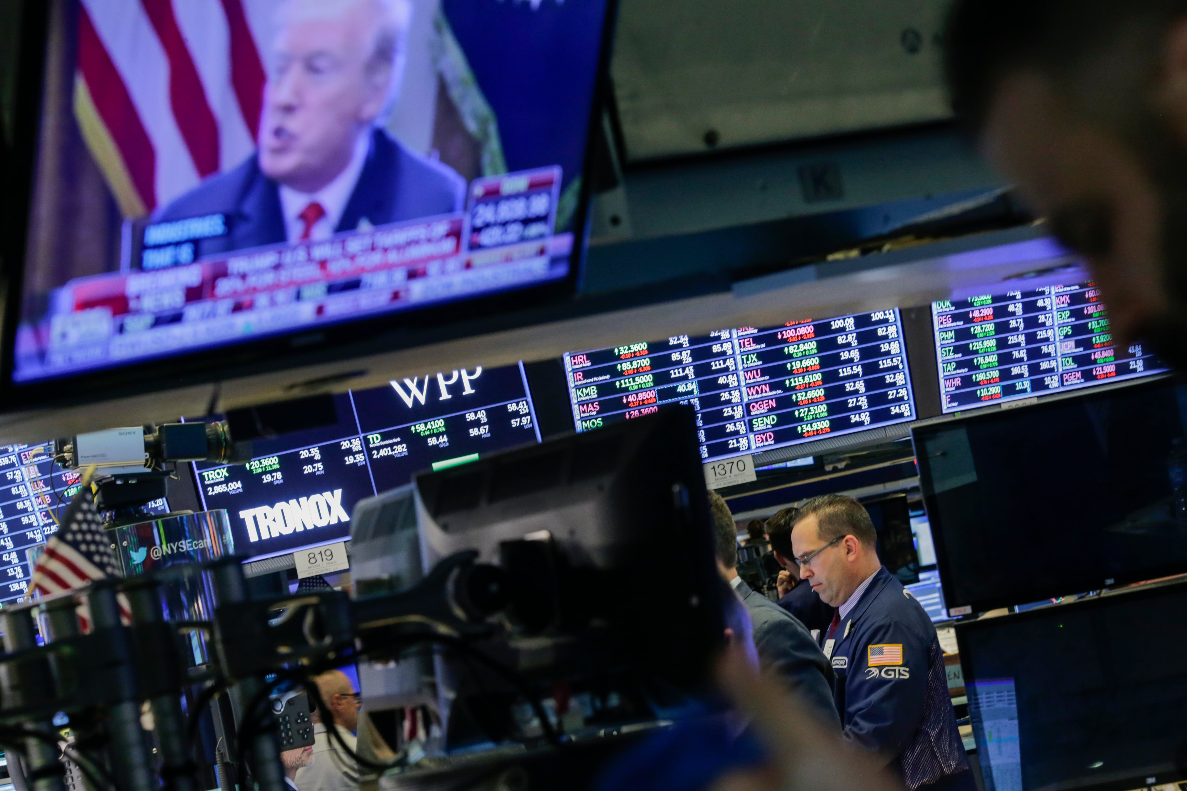 Traders work on the floor of the New York Stock Exchange (NYSE) as U.S. President Donald Trump is seen on TV.