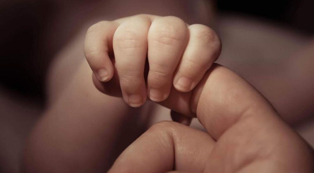 La mano del niño coge un dedo de Marta.