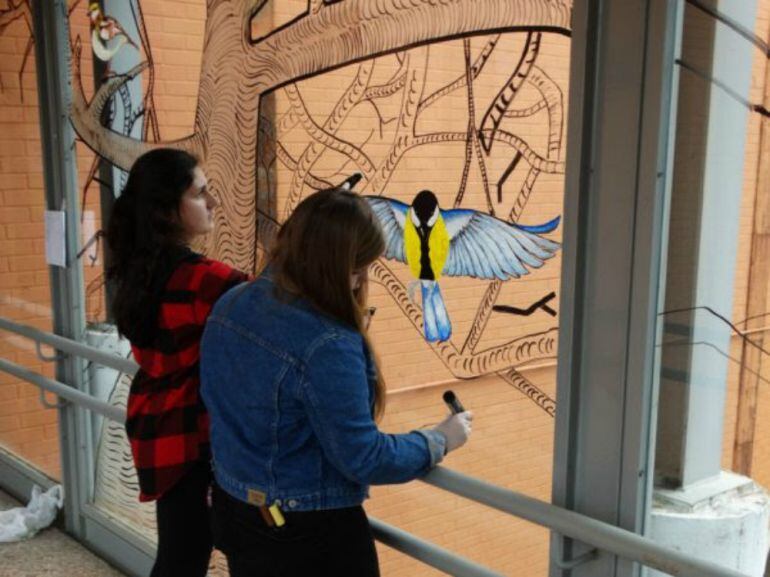  Estudiantes de Arte decorando una cristalera en el campus universitario.