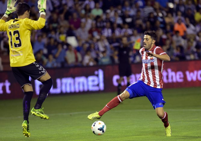 El delantero del Atlético de Madrid, David Villa (d), controla el balón frente al portero Diego Mariño, del Real Valladolid