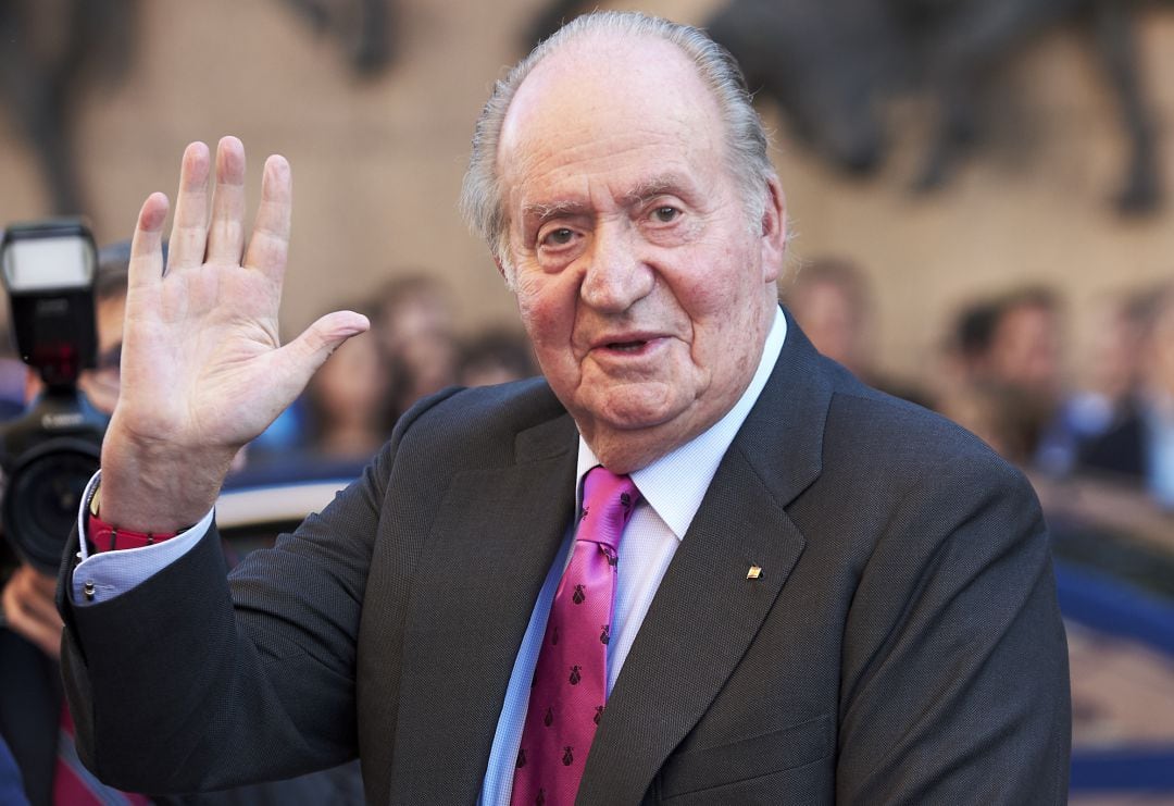 El rey emérito, Juan Carlos I, saluda con la mano