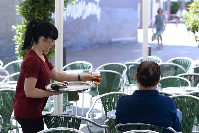 Una camarera sirve una consumición en una terraza.