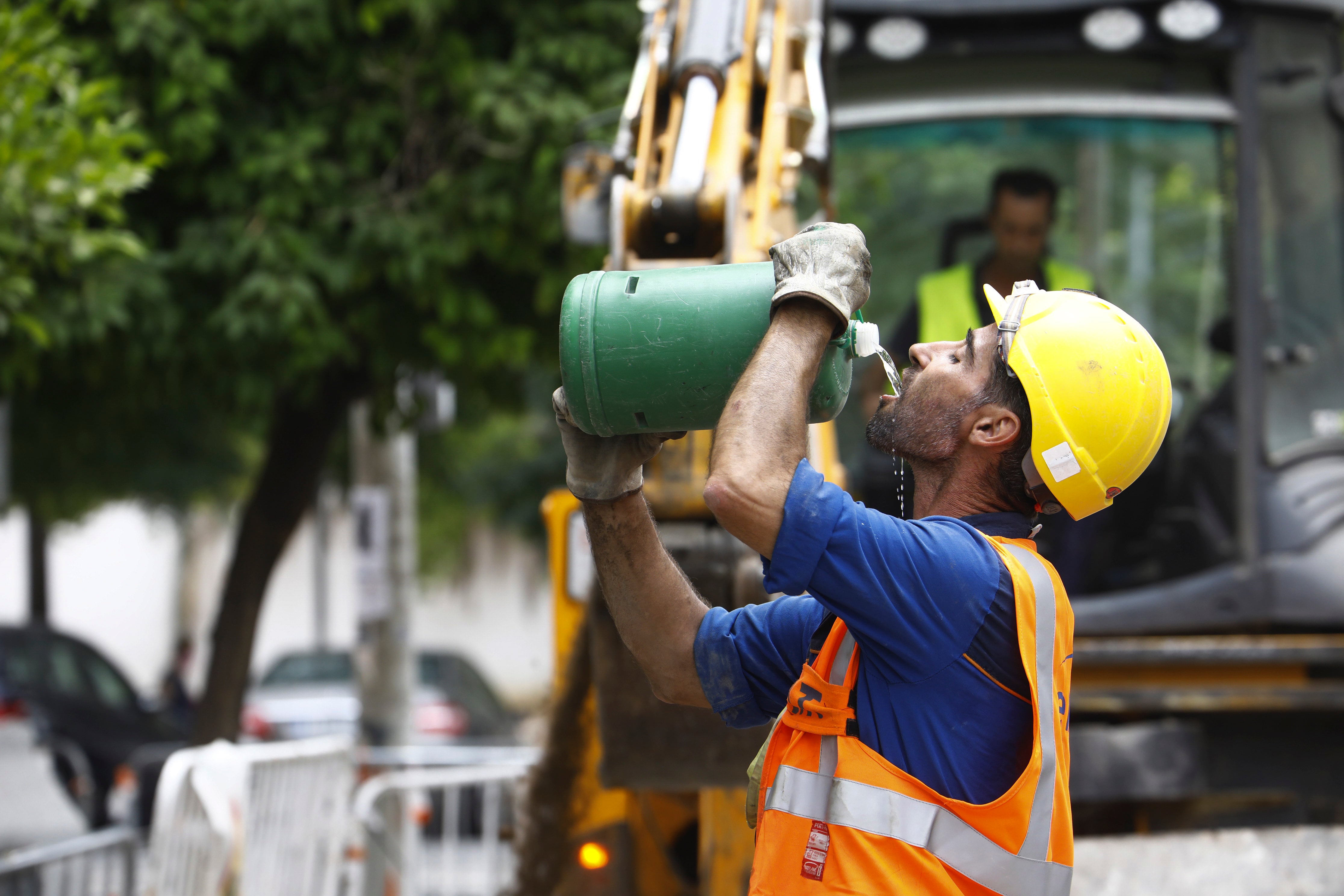 Fotografía de archivo de un trabajador de la construcción bebiendo agua durante la jornada de trabajo en plena ola de calor.