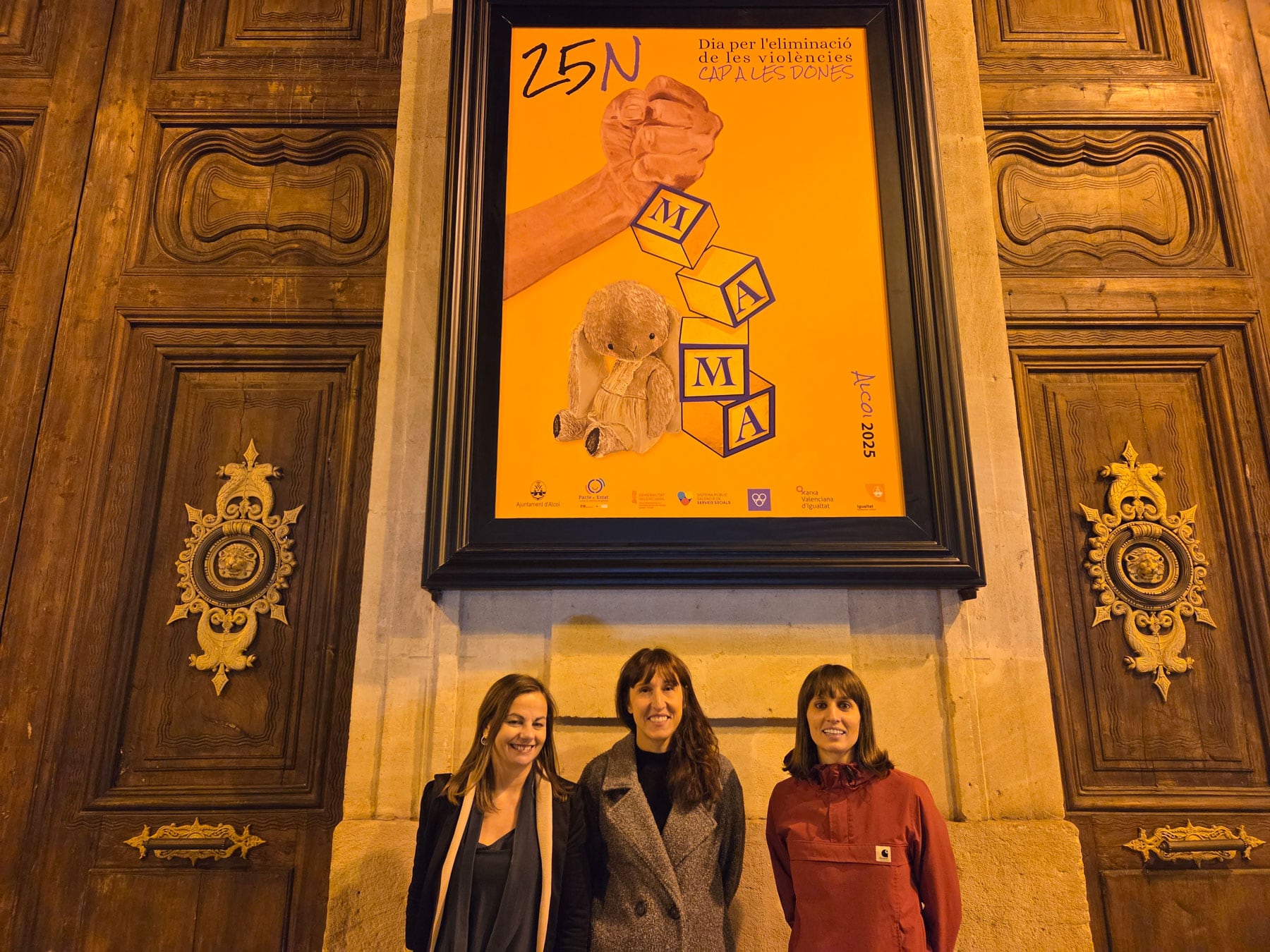 Rut Tomás, Lola Llopis y Alicia López, ante el cartel de Lola con motivo del 25N