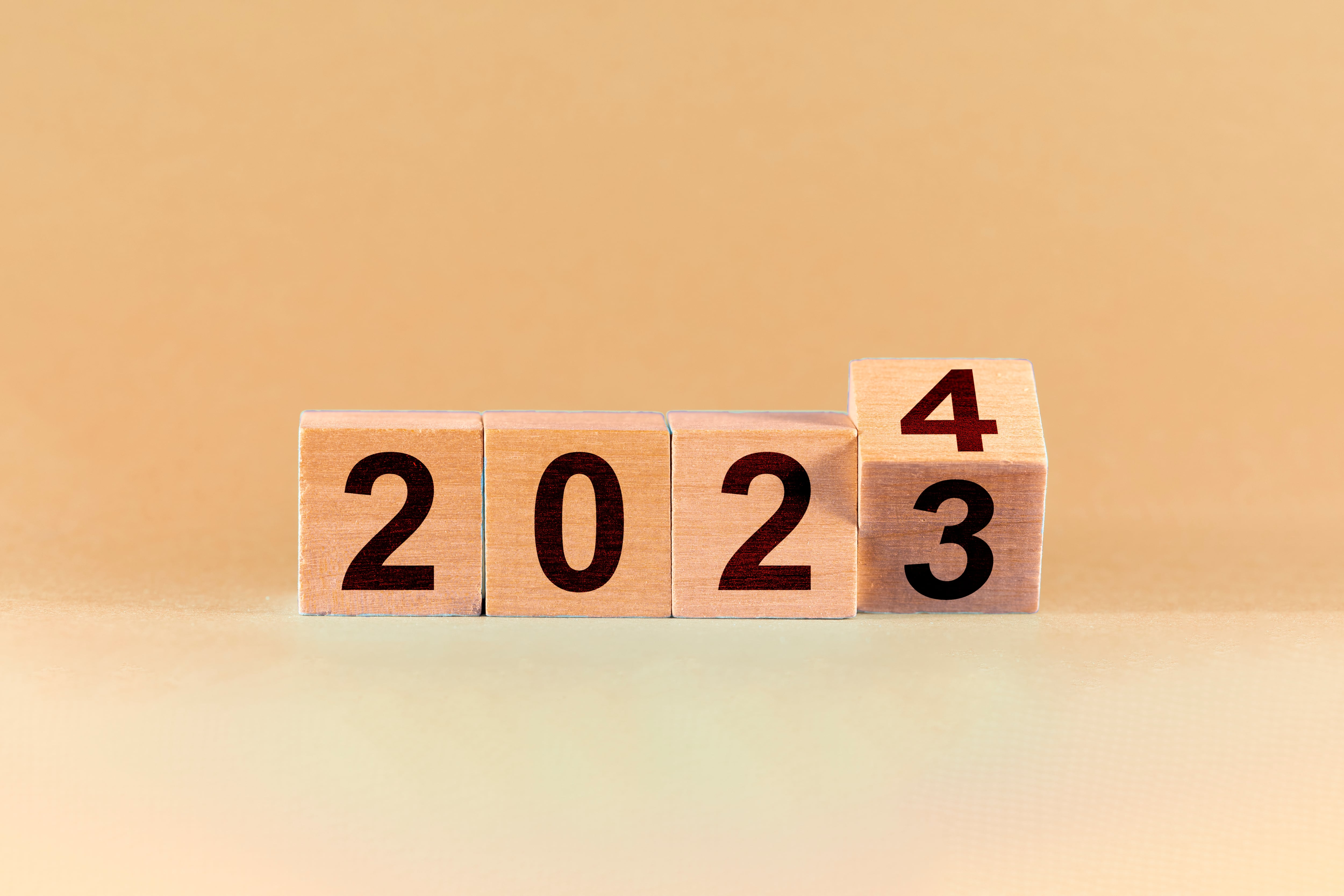 Concept of the end of 2023 and the new beginning in 2024. Change from 2023 to 2024 in wooden cubes on a coloured background.