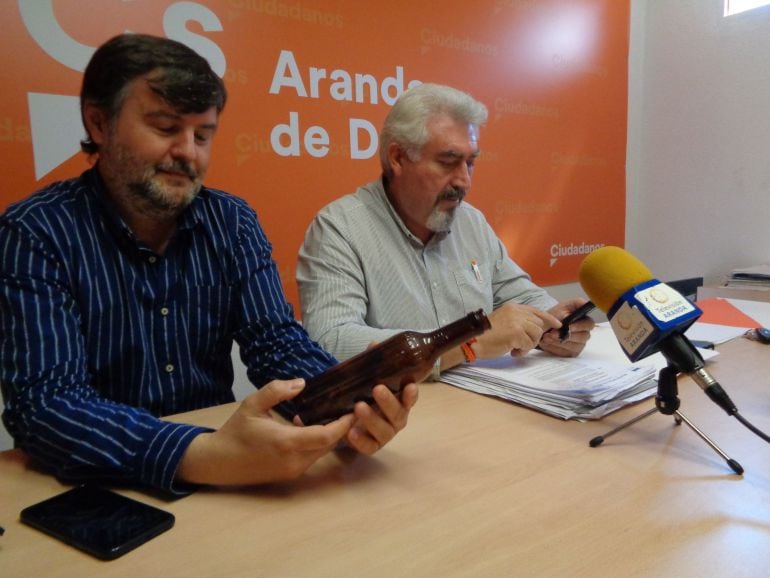 Francisco Martín Hontoria sostiene una de las botellas de la carga del camión accidentado, con José Ignacio Delgado en segundo término