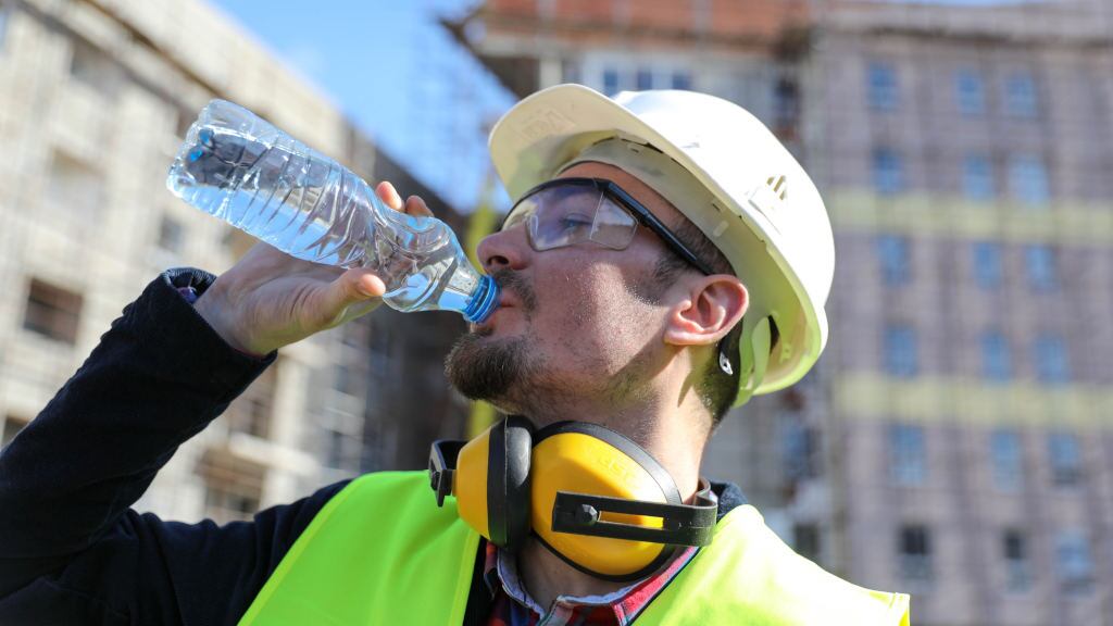 Un trabajador de la construcción bebiendo agua