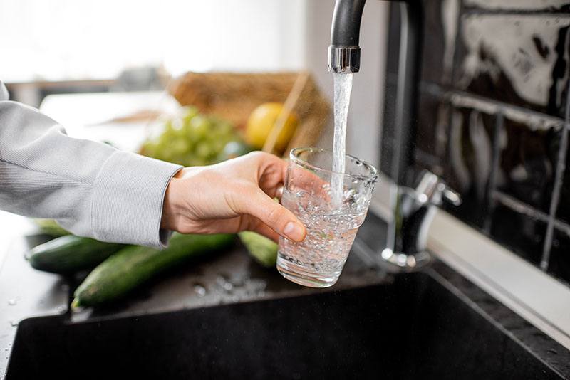 Una mujer cogiendo agua del grifo.