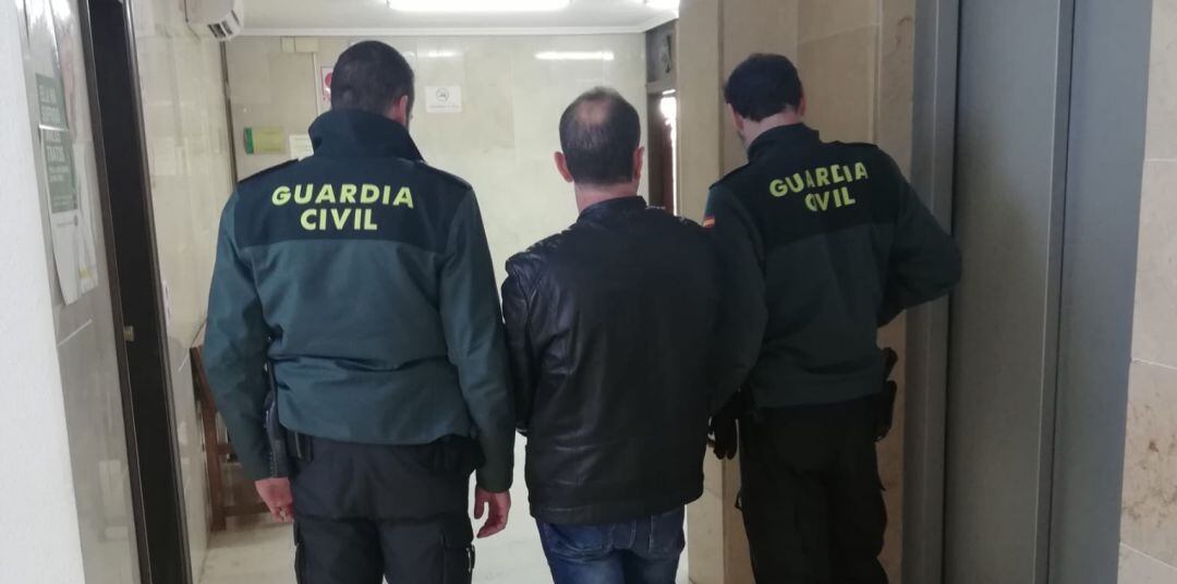 Uno de los detenidos junto a dos guardias civiles.