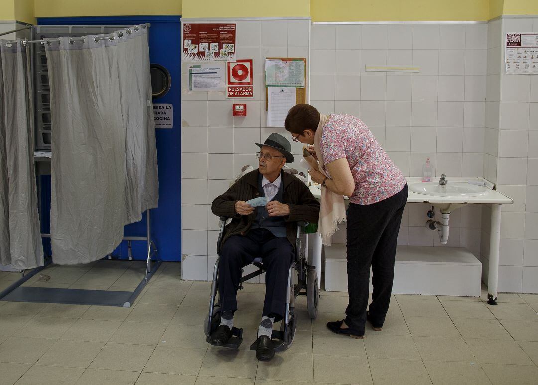 Imatge d'arxiu d'un home gran en cadira de rodes en un col·legi electoral