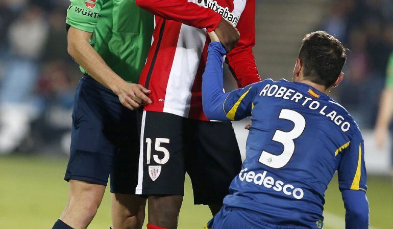 El delantero del Athletic Club Iñaki Williams (c), junto al árbitro Javier Estrada (i) ayuda a levantarse al defensa del Getafe Roberto Lago, durante el partido correspondiente a la vigésima segunda jornada de liga
