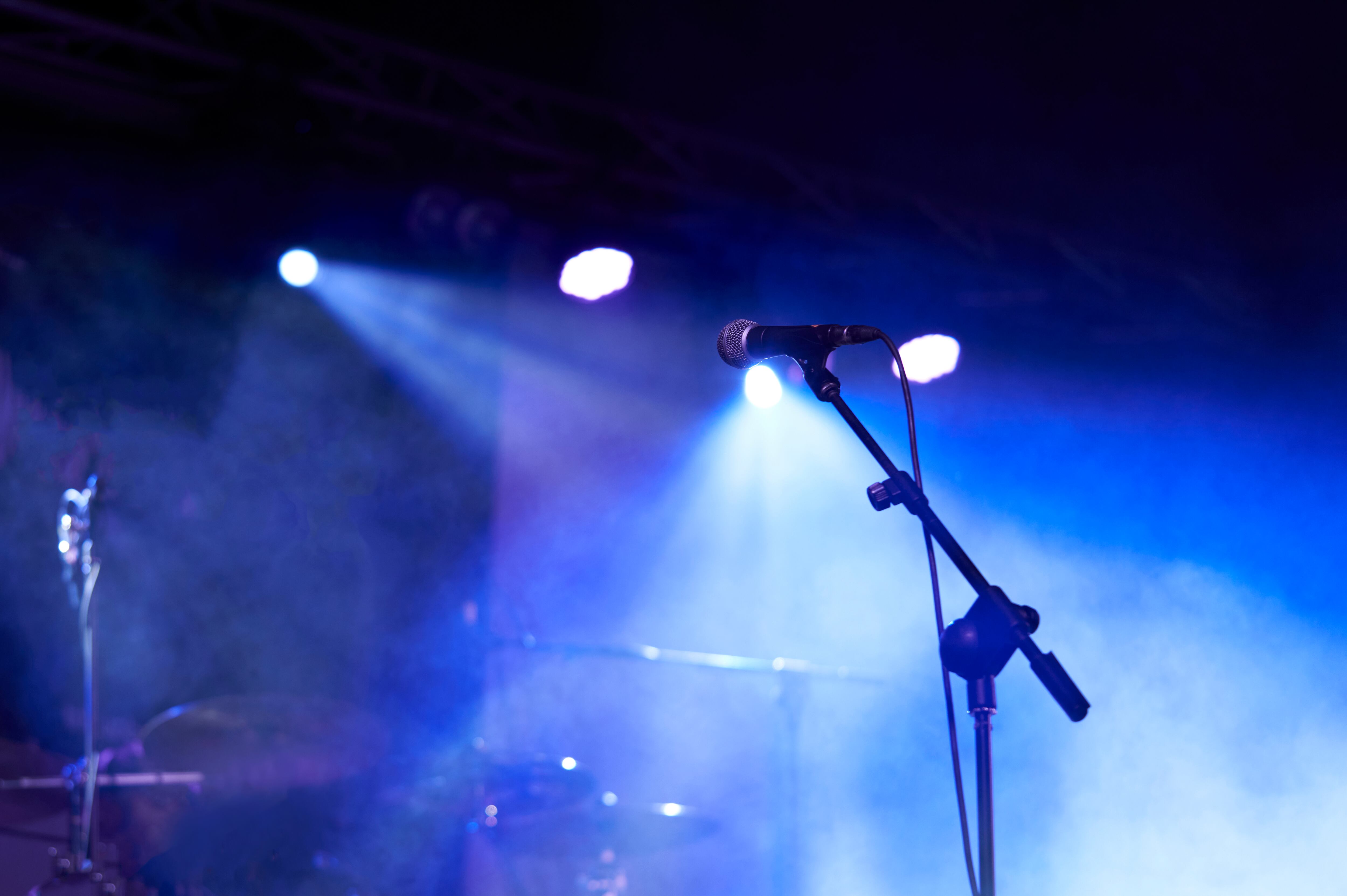 Rear view low angle view of a microphone and spotlights on stage at a live concert with musical instruments background