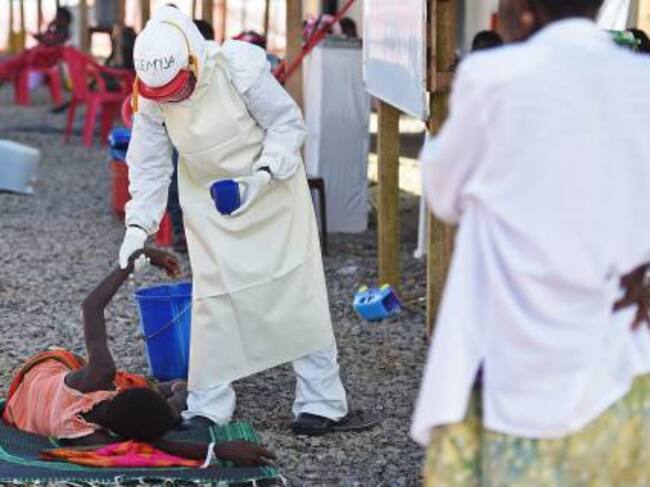 A health worker wearing protective equipment assists an Ebola patient at the Kenama treatment centre run by the Red Cross Society on November 15, 2014. Ebola-hit Sierra Leone faces social and economic disaster as gains made since the country's ruinous civ