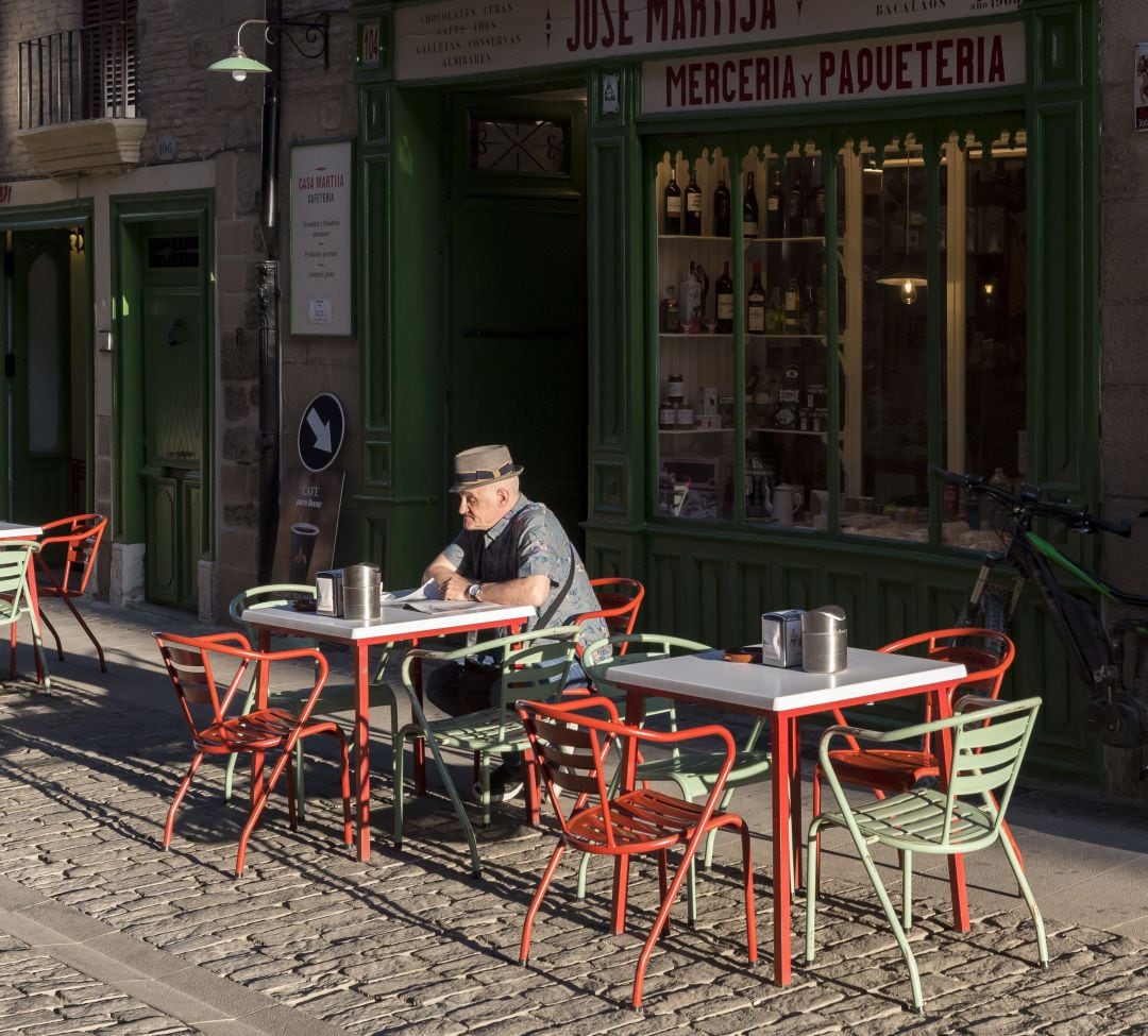 Un anciano toma un café en la terraza de un bar.