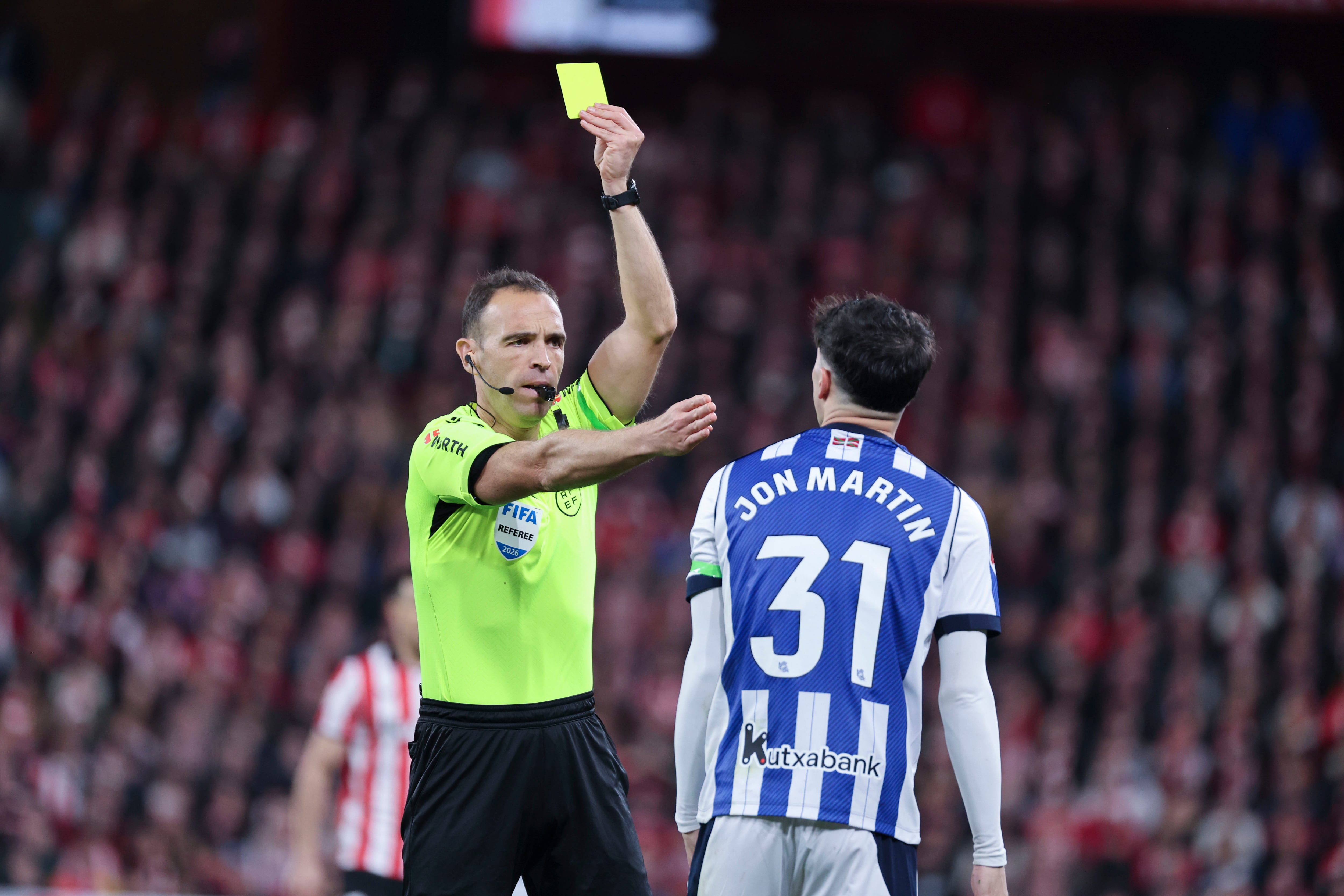 BILBAO, 01/02/2026.- El defensa de la Real Sociedad Jon Martín (d) ve una tarjeta amarilla durante el encuentro correspondiente a la jornada 22 que Athletic Club y Real Sociedad disputan hoy domingo en el estadio de San Mamés, en Bilbao. EFE / Luis Tejido