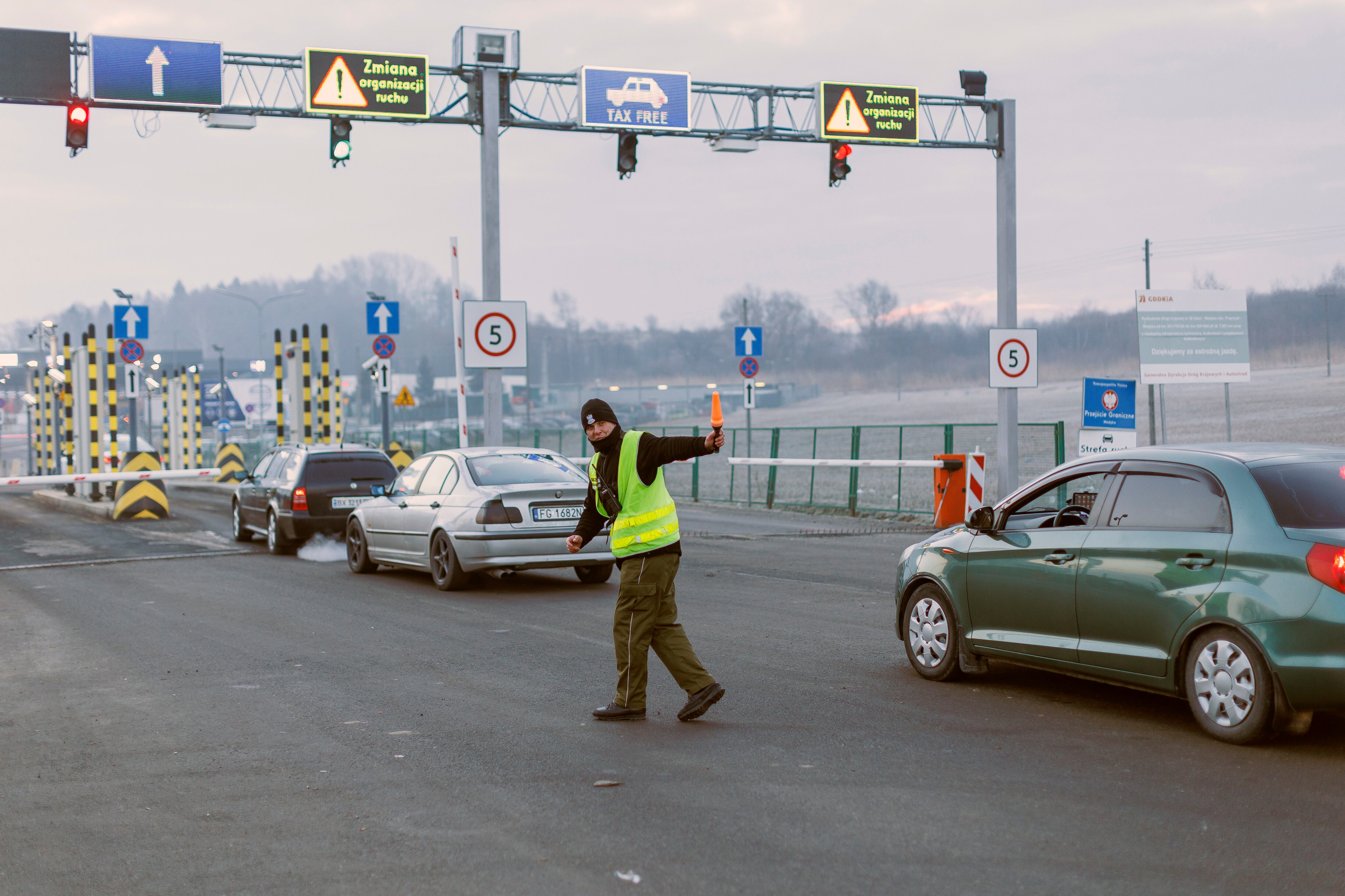 GRAF6615. MEDYKA (POLONIA), 27/02/2022.- Una persona controla el tráfico en la frontera con Ucrania, donde cientos de ciudadanos han cruzado, hoy domingo, huyendo de la guerra. EFE / Biel Aliño.