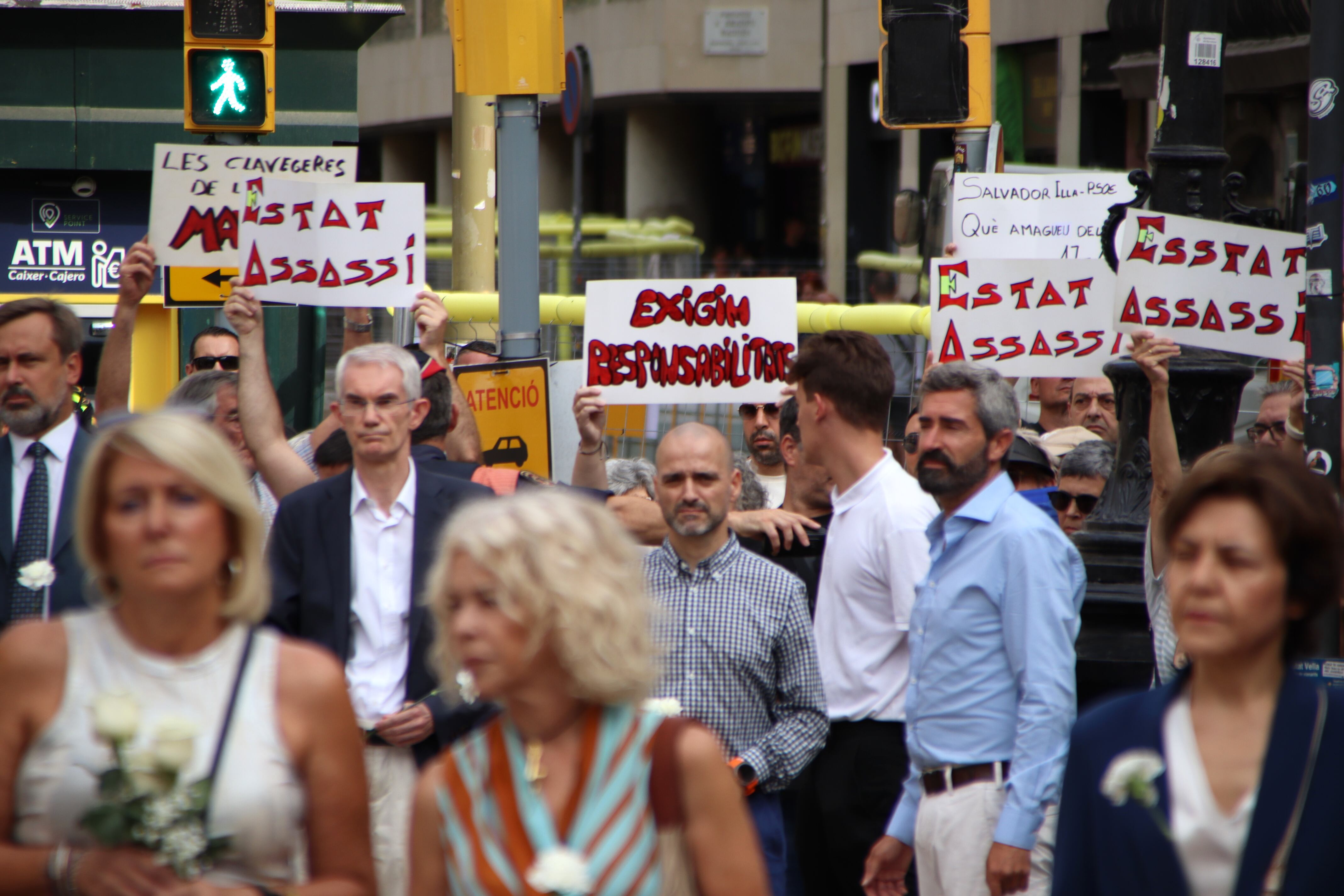 Algunes persones al marge de l&#039;acte oficial mostren cartells de protesta.
