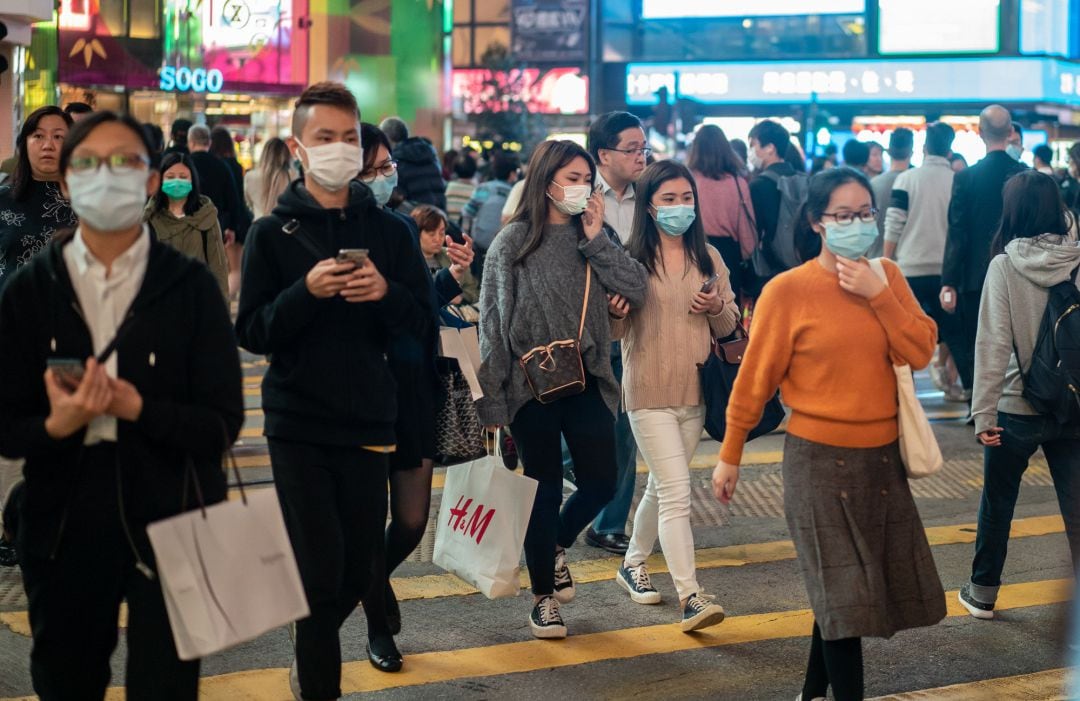 peatones usan mascarillas mientras caminan por un cruce peatonal en el distrito de Causeway Bay en Hong Kong, China.