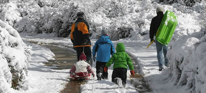 Una familia disfruta de la nieve en su paseo por un camino rural de Prades (Tarragona). Gran parte de Cataluña ha amanecido teñida de blanco por las nevadas que han caído en las últimas horas en cotas inusualmente bajas, sobre todo del litoral.