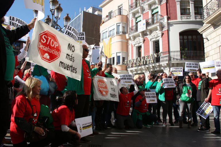 Manifestants de la PAH, en rotllana, mostrant cartells de protesta per la mort d'una àvia en situació de pobresa a Reus, a la plaça del Mercadal, davant del consistori