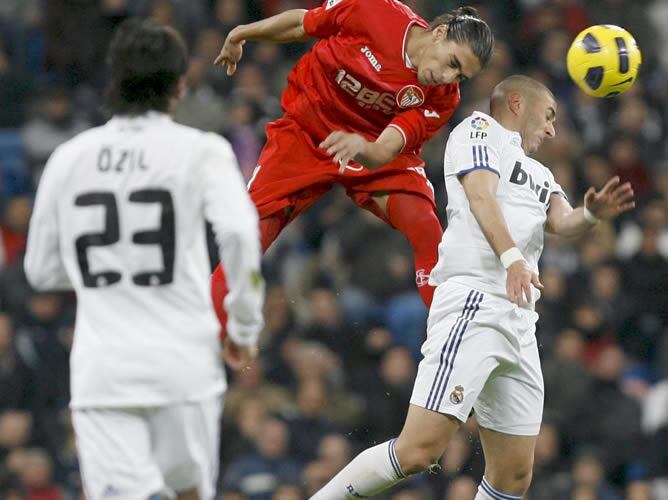 El defensa uruguayo del Sevilla Martín Cáceres cabecea un balón ante el delantero francés del Real Madrid Karim Benzema