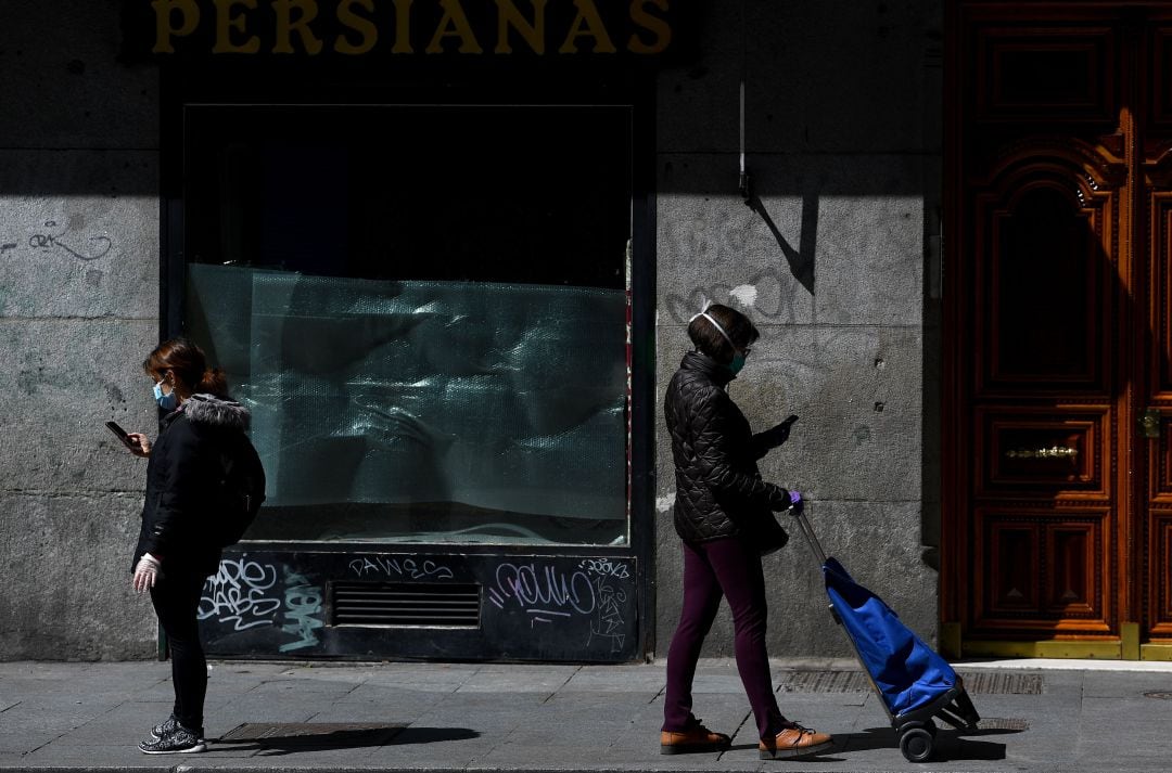 Dos personas en la calle con mascarillas.