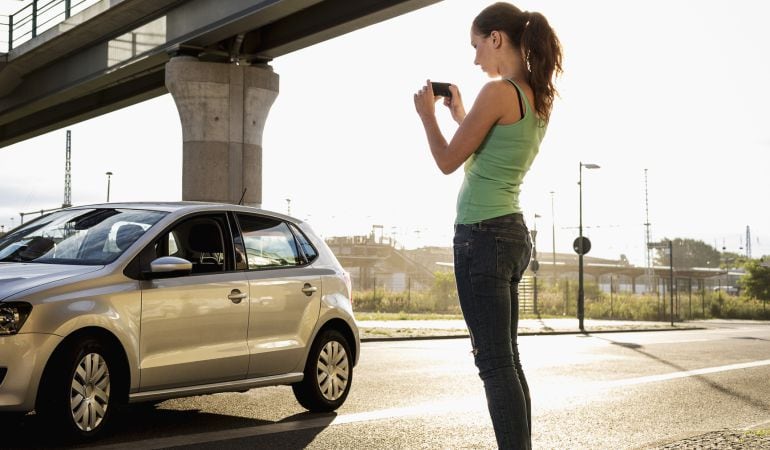 Una mujer sacando una foto a un coche.