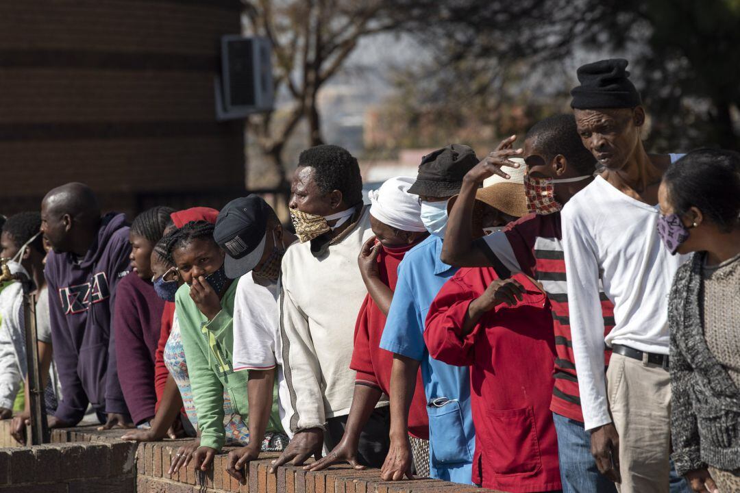 Gente con mascarilla en una cola para el reparto de comida en Johannesburgo, Sudáfrica.